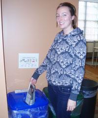 student putting paper in a recycling bin